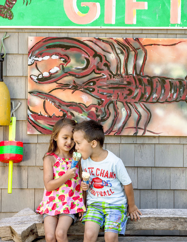 Two kids eating ice-cream outside by a lobster painting