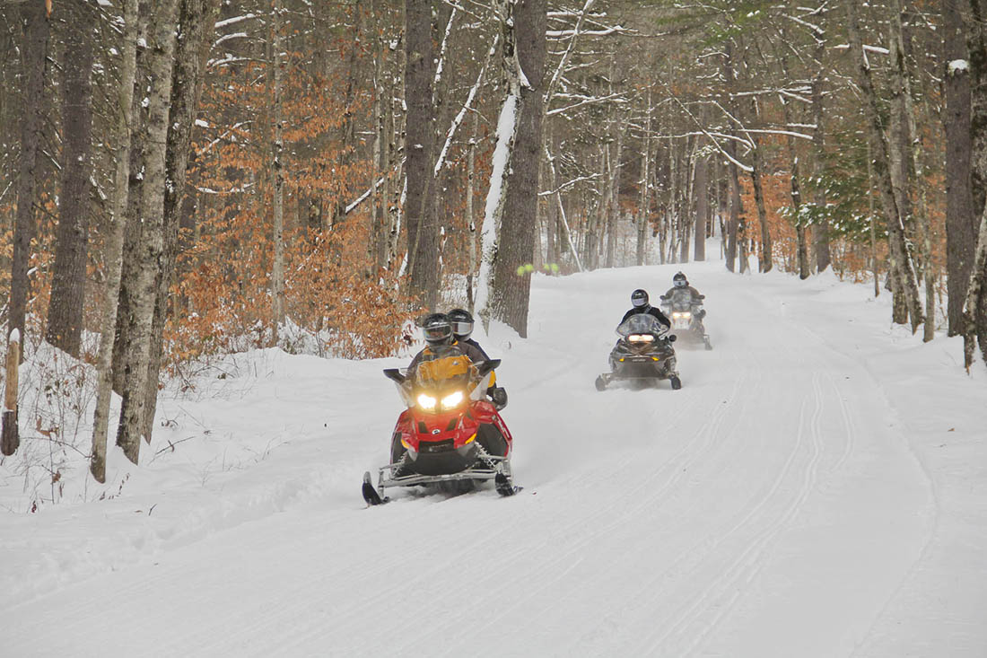 A group of people snowmobiling on a trail