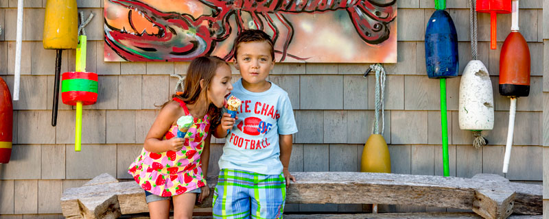 Two kids eating ice-cream outside by a lobster painting