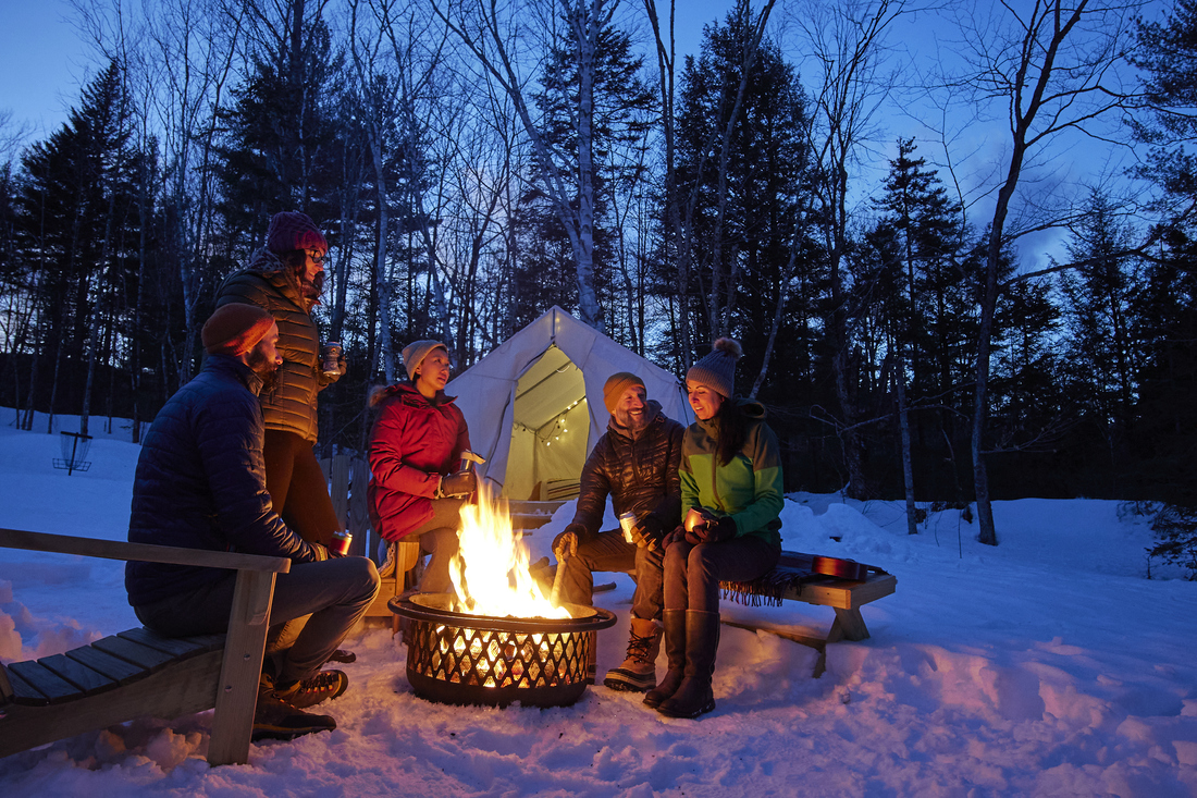 Family camping and sitting by a fire at night