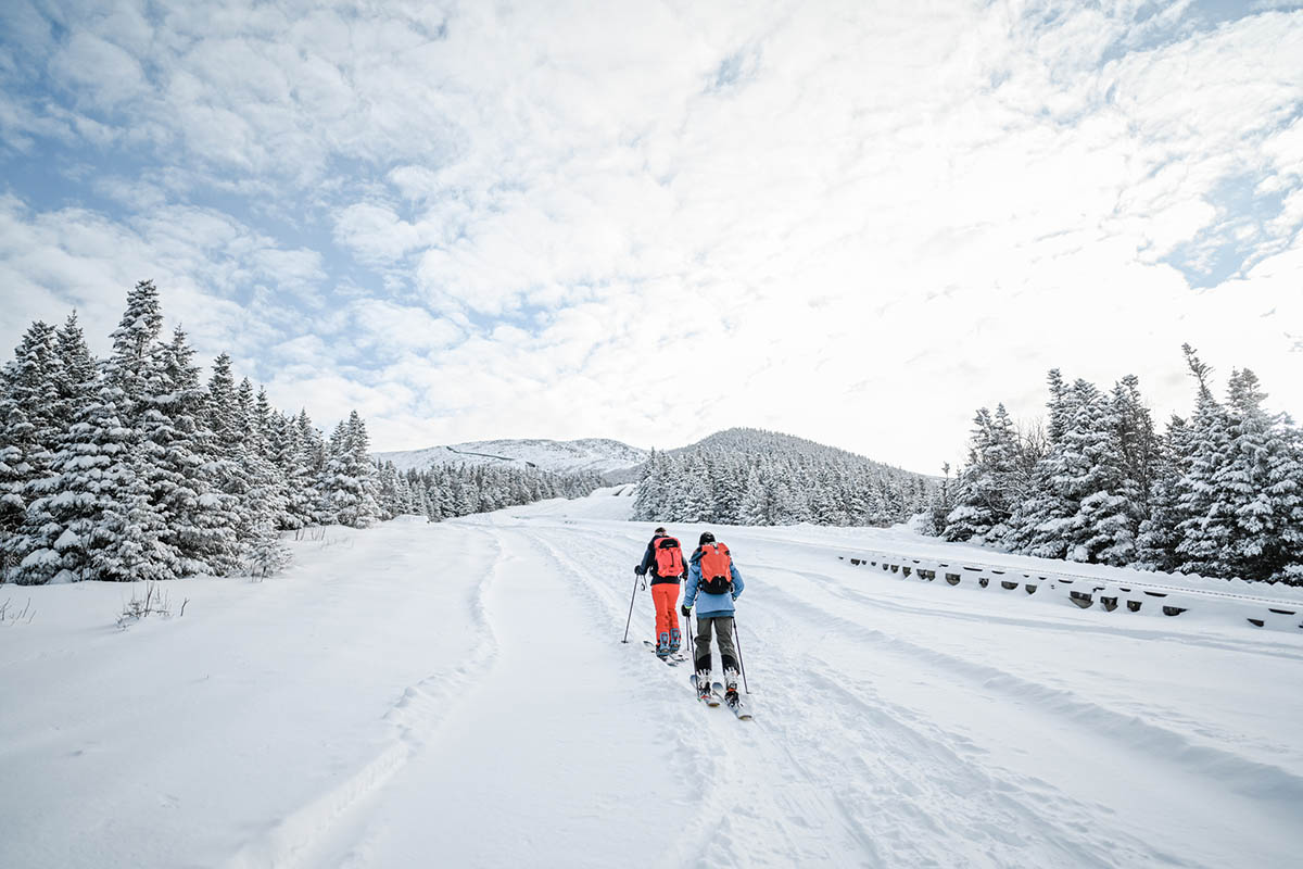 2 people walking in the snow with skis on