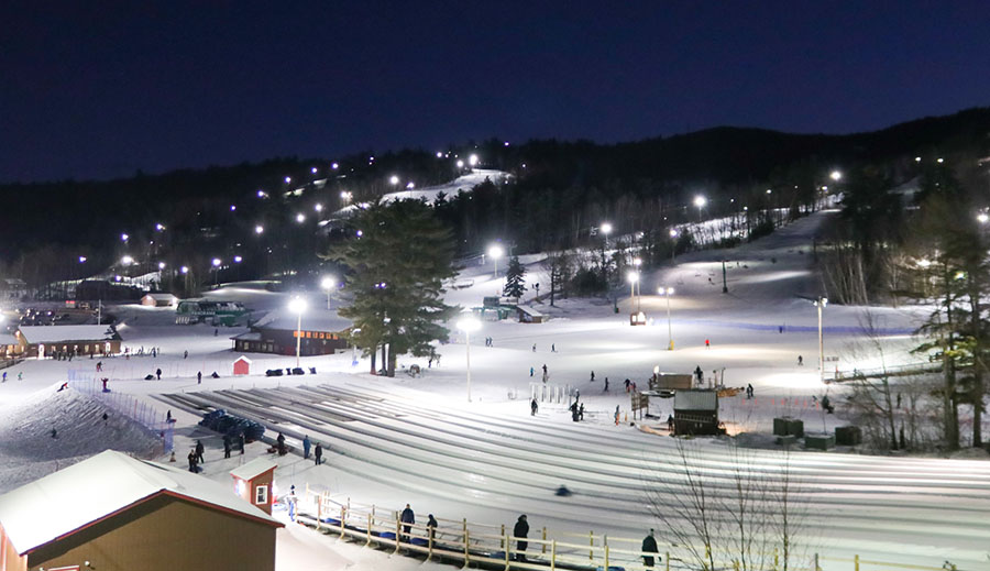 a view of a tubing hill and ski area at night under lights