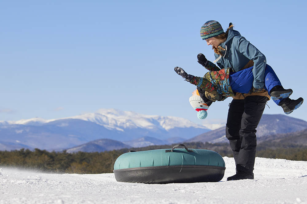 a woman holding a child over a snowtube