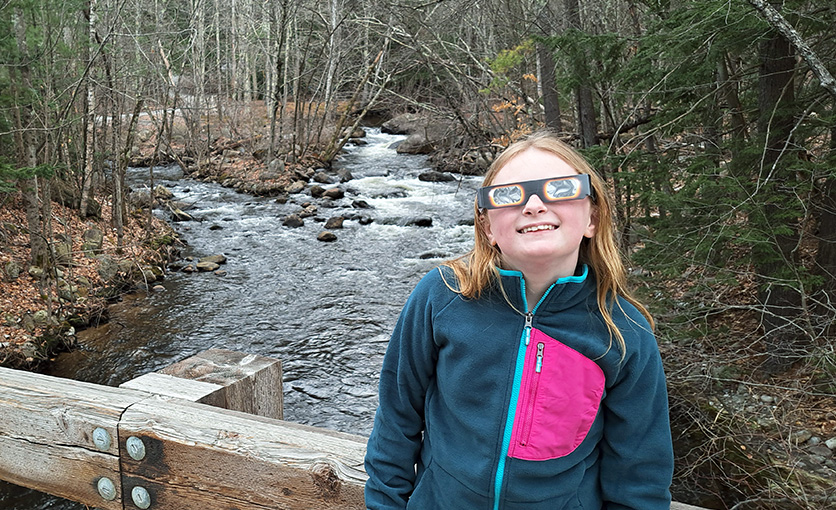 a girl wearing eclipse glasses