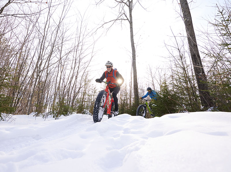 2 people riding bikes in the snow