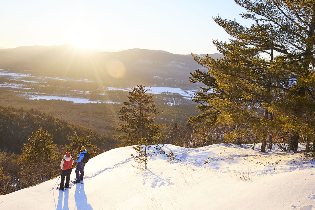 2 people standing in the snow at the top of a mountain